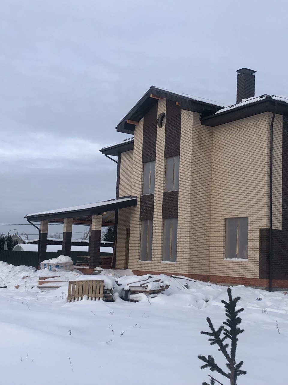 Боковой фасад кирпичного дома с навесом и колоннами